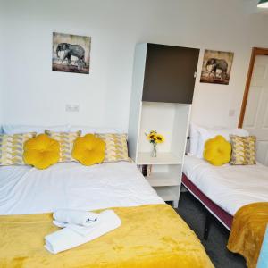 two beds in a room with yellow pillows at Sheridan House - En-suite Bedrooms I Long or Short Stay I Special Rate Available in Derby
