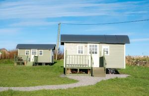 a small house with a black roof on a grass field at Wild Meadow Huts in Doolin