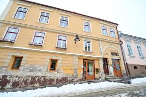 a large yellow building on a snowy street at The Oracle Downtown Apartment in Sibiu