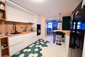 a kitchen with white cabinets and a green and white floor at The Oracle Downtown Apartment in Sibiu
