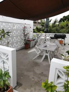 a patio with white tables and chairs and plants at Okinawan. Sweet Home. T-8 in Chatan