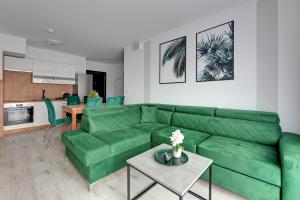 a living room with a green couch and a table at Downtown Apartments Riverside Dwie Motławy in Gdańsk