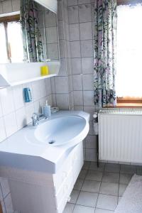 La salle de bains blanche est pourvue d'un lavabo et d'une fenêtre. dans l'établissement Ferienwohnung Schwabenhof, à Leutershausen