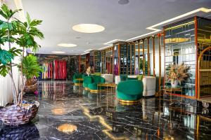 un hall avec des chaises vertes, des tables et des plantes dans l'établissement One Hotel Casablanca, à Casablanca