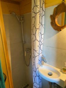 a bathroom with a sink and a shower with a shower curtain at Tree House Alpinka Krvavec in Cerklje na Gorenjskem