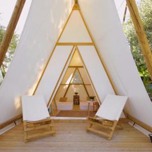 twee stoelen en een tafel in een driehoekige tent bij Kampaoh Grazalema in El Bosque