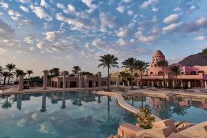 uma grande piscina com palmeiras e um edifício em Mosaique Beach Resort Taba Heights em Taba