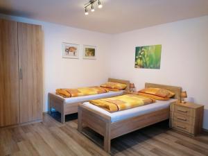 two twin beds in a room with wooden floors at Pension Stern in Rauenberg