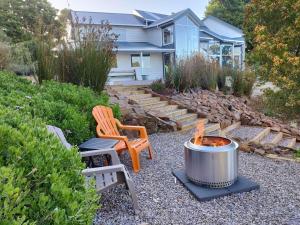 een achtertuin met een vuurplaats, een stoel en een huis bij Skyescape on Northshore in Table Cape
