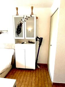 Cette chambre comprend une armoire blanche avec un miroir. dans l'établissement Chez Jorge et Mae - Studio 4 pers. La Frégate - Grau du Roi- France, au Grau-du-Roi