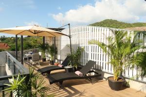 een balkon met stoelen, een parasol en planten bij Seaflower Bungalows in Srithanu