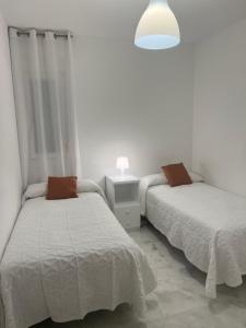 2 Betten in einem weißen Zimmer mit einer Lampe in der Unterkunft Casa vacacional equipada in Lebrija