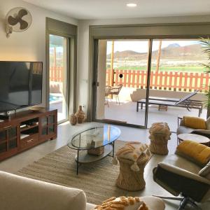 ein Wohnzimmer mit Sofa und Fernseher in der Unterkunft Golf Tenerife South xx Wheel Accessible Shower xx Free WIFi xx Private Pool 30 degrees xx Two Terraces 30m2x60m2 xxFree Parking xx Mountain view xx Flatscreen 65 inch xx in San Miguel de Abona