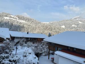 a house covered in snow with mountains in the background at Holiday Home Chalet Walchsee by Interhome in Sachrang