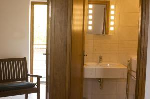 ein Badezimmer mit einem Waschbecken, einem Spiegel und einem Stuhl in der Unterkunft Frittmann Borház in Soltvadkert