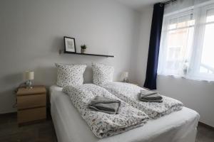 a bedroom with a bed with white sheets and a window at Apartments am Lindengraben in Emden