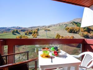 a table on a balcony with a view of a mountain at Apartment Lunik Orion-22 by Interhome in Le Corbier