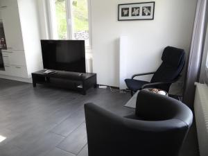 - un salon avec deux chaises et une télévision à écran plat dans l'établissement Apartment Barbara Ost by Interhome, à Engelberg