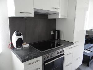 une cuisine avec des placards blancs et un comptoir noir dans l'établissement Apartment Barbara Ost by Interhome, à Engelberg