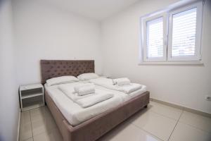 Bett in einem weißen Zimmer mit Fenster in der Unterkunft Villa San Antonio-exclusive apartments in Baška