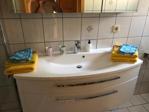 La salle de bains est pourvue d'un lavabo, de serviettes jaunes et d'un miroir. dans l'établissement Ferienwohnung Näfelt, à Gunzenhausen