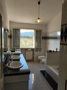 a bathroom with three sinks and a tub and a window at Da Maurizio e Luisa in Castiadas +11 photos