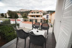 einen Balkon mit 4 Stühlen, einem Tisch und einem Gebäude in der Unterkunft Villa San Antonio-exclusive apartments in Baška