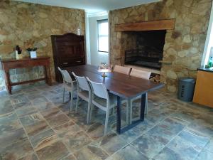 a dining room with a table and a stone fireplace at Kudukloof 