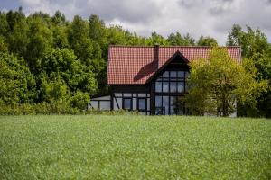 una casa con un tetto rosso in cima a un campo di Hotel SPA Dr Irena Eris Wzgórza Dylewskie - Siedliska a Wysoka Wieś