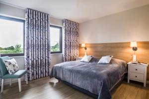 a bedroom with a bed and a chair and a window at Hotel SPA Dr Irena Eris Wzgórza Dylewskie - Siedliska in Wysoka Wieś