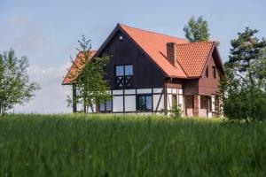 una casa nera con un tetto arancione in cima a un campo di Hotel SPA Dr Irena Eris Wzgórza Dylewskie - Siedliska a Wysoka Wieś