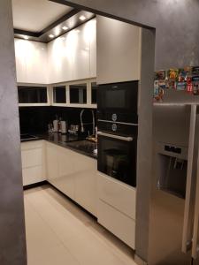 una cocina con armarios blancos y electrodomésticos negros en Urban Home Sweet Home & Parking, en Belgrado