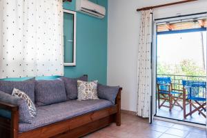 sala de estar con sofá y balcón en Nemorosa Holiday Houses, en Méson Yerakaríon