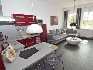 eine Küche und ein Wohnzimmer mit roten Schränken in der Unterkunft Villa "To Hus" F590 - Appartement 01 im EG mit Kamin und Terrasse in Ostseebad Sellin