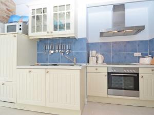 オストゼーバート・ゼリンにあるVilla "To Hus" F590 - Appartement 06 im Dachgeschoss mit Balkonの白いキャビネットと青いタイルのキッチン