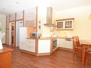 a kitchen with white cabinets and a wooden floor at Villa "To Hus" in Sellin - WG 02 mit Kamin und Balkon in Ostseebad Sellin