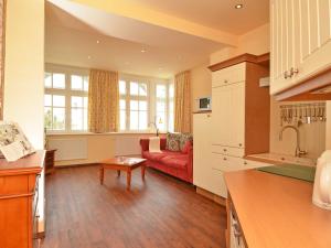 eine Küche und ein Wohnzimmer mit einem roten Sofa in der Unterkunft Villa "To Hus" F590 - Appartement 03 im ersten OG mit Balkon in Ostseebad Sellin