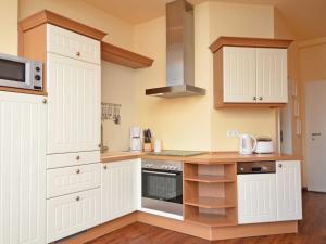 eine Küche mit weißen Schränken und einer Mikrowelle in der Unterkunft Villa "To Hus" F590 - Appartement 03 im ersten OG mit Balkon in Ostseebad Sellin