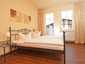 um quarto com uma cama com lençóis brancos e uma janela em Villa "To Hus" F590 - Appartement 03 im ersten OG mit Balkon em Ostseebad Sellin