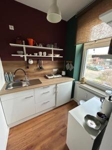 eine Küche mit weißen Schränken, einem Waschbecken und einem Fenster in der Unterkunft Buntes Haus in Erfurt