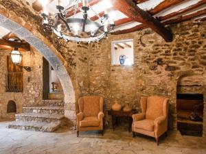 Habitación de piedra con 2 sillas y lámpara de araña. en Holiday Home Mas d'en Tarres by Interhome, en Vespellà