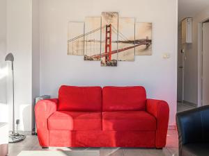 Un sofá rojo en una sala de estar con un cuadro de un puente. en Apartment Les Galiotes-3 by Interhome, en Carnac 18 fotos más