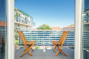 2 Stühle auf einem Balkon mit Blick auf ein Gebäude in der Unterkunft Apartmani Gabriella in Vodice