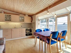 a kitchen with a dining room table and blue chairs at Apartment Genadij - 1km from the sea in Western Jutland by Interhome in Vejers Strand