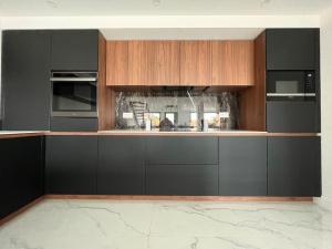 a kitchen with black and wooden cabinets and appliances at La Villa Nina in Mirepeisset