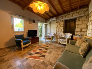 a living room with a couch and chairs and a tv at La Maison de Yasmine in Alaçatı