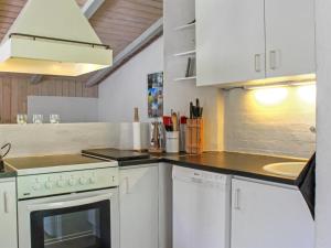 a kitchen with white cabinets and a stove top oven at Holiday Home Gerarda - 4km from the sea in NE Jutland by Interhome in Læsø
