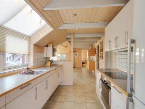 a large kitchen with white cabinets and a large window at Holiday Home Drusilla - 800m from the sea in Western Jutland by Interhome in Hvide Sande