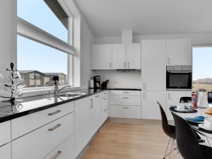 a white kitchen with white cabinets and a table at Holiday Home Gerniot - 500m from the sea in NE Jutland by Interhome in Frederikshavn