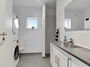 a white bathroom with a sink and a washing machine at Holiday Home Gerniot - 500m from the sea in NE Jutland by Interhome in Frederikshavn